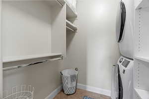 Clothes washing area with light tile patterned floors and stacked washer / dryer