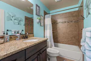 Full bathroom featuring shower / bath combo with shower curtain, vanity, a textured ceiling, and toilet