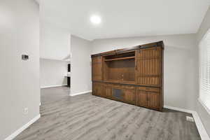 Unfurnished living room featuring lofted ceiling and light hardwood / wood-style flooring