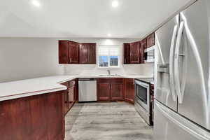 Kitchen with stainless steel appliances, sink, and light hardwood / wood-style flooring