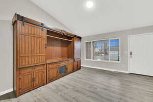 Interior space featuring vaulted ceiling, light hardwood / wood-style floors, and a barn door