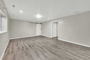 Empty room featuring a barn door and light hardwood / wood-style flooring