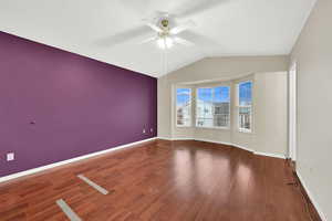 Empty room with ceiling fan, dark hardwood / wood-style floors, and vaulted ceiling