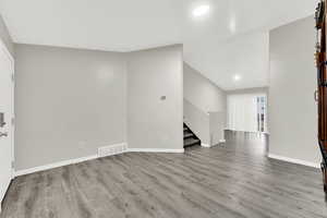 Unfurnished living room with vaulted ceiling and light wood-type flooring