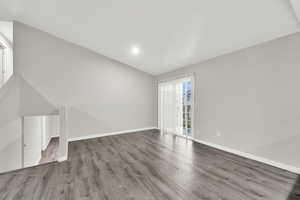 Unfurnished living room with hardwood / wood-style flooring and vaulted ceiling