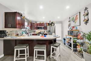 Kitchen with light wood-type flooring, stainless steel appliances, and a breakfast bar area