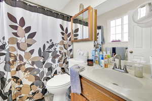 Bathroom featuring walk in shower, vanity, and toilet