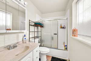 Full bathroom featuring tile patterned flooring, vanity, toilet, and enclosed tub / shower combo