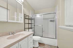 Full bathroom with vanity, toilet, and combined bath / shower with glass door