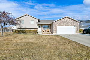 Split level home with a porch, a garage, and a front lawn