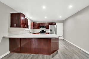 Kitchen featuring appliances with stainless steel finishes, sink, light wood-type flooring, and kitchen peninsula