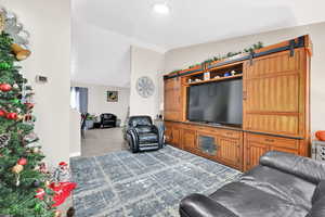 Living room with dark hardwood / wood-style floors, a barn door, and lofted ceiling