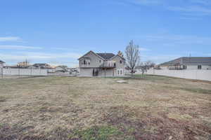 Rear view of house featuring a wooden deck and a lawn