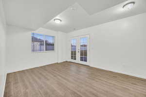 Empty room with french doors, a textured ceiling, and light hardwood / wood-style flooring