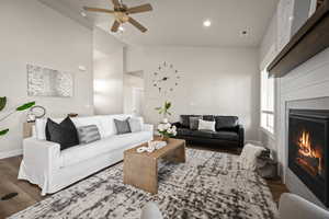 Living room with dark hardwood / wood-style flooring, ceiling fan, lofted ceiling, and a tiled fireplace