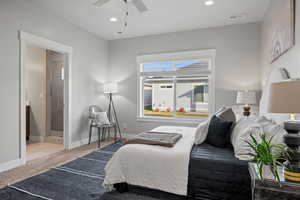 Bedroom with ensuite bath, ceiling fan, and light carpet