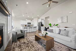 Living room featuring a tile fireplace, ceiling fan, dark hardwood / wood-style floors, and lofted ceiling