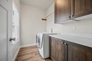 Laundry area featuring plenty of natural light, cabinets, independent washer and dryer, and light hardwood / wood-style flooring