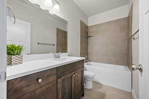 Full bathroom featuring vanity, tile patterned floors, tiled shower / bath combo, and toilet