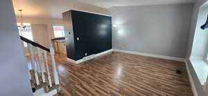 Living room featuring wood-style flooring, vaulted ceiling and green accent wall