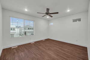 Empty room featuring ceiling fan and dark hardwood / wood-style flooring