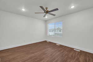 Empty room with ceiling fan and dark hardwood / wood-style flooring