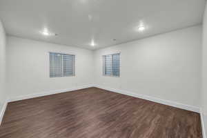 Empty room featuring a textured ceiling and dark hardwood / wood-style floors