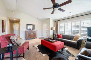 Carpeted living room with a textured ceiling, ceiling fan, and lofted ceiling