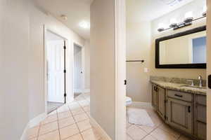 Bathroom with tile patterned flooring, a textured ceiling, vanity, and toilet