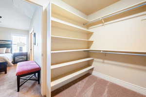 Walk in closet with carpet flooring and lofted ceiling