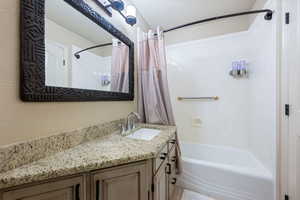 Bathroom featuring shower / bath combo with shower curtain and vanity