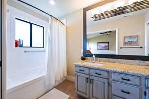 Bathroom with ceiling fan, vanity, shower / bath combination with curtain, and vaulted ceiling