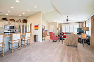 Living room with light carpet, ceiling fan, and lofted ceiling