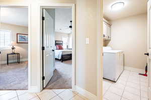 Laundry area featuring light carpet, washing machine and dryer, ceiling fan, and cabinets