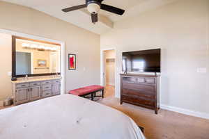 Carpeted bedroom featuring ensuite bath, vaulted ceiling, ceiling fan, a spacious closet, and a closet