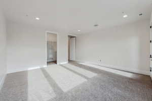 Unfurnished bedroom featuring a walk in closet and light colored carpet