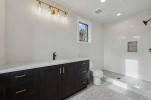 Bathroom featuring tile patterned floors, vanity, toilet, and a tile shower