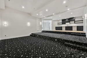 Carpeted home theater room featuring beam ceiling and Kitchenette