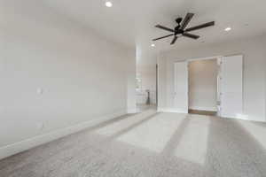 Interior space featuring ceiling fan, light carpet, and connected bathroom