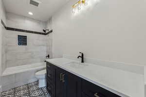 Full bathroom featuring vanity, toilet, and tiled shower / bath