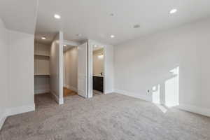 Unfurnished bedroom featuring light carpet, a walk in closet, ensuite bath, and a closet