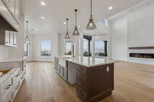 Kitchen with pendant lighting, a large fireplace, white cabinets, and sink