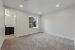 Unfurnished bedroom featuring ensuite bathroom and light carpet