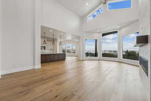 Unfurnished living room with beam ceiling, light hardwood / wood-style floors, and high vaulted ceiling