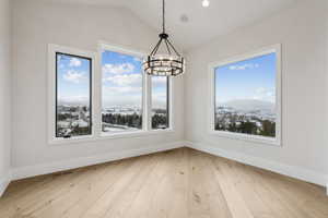 Unfurnished dining area featuring a mountain view, lofted ceiling, light hardwood / wood-style flooring, and a chandelier