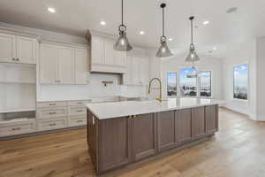 Kitchen featuring lofted ceiling, decorative light fixtures, light hardwood / wood-style flooring, and a large island