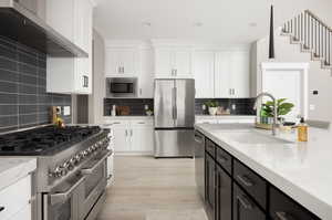 Kitchen with sink, wall chimney exhaust hood, light stone counters, decorative light fixtures, and appliances with stainless steel finishes