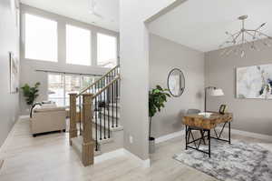 Stairs with hardwood / wood-style floors and a notable chandelier