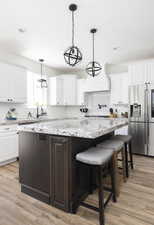 Kitchen featuring white cabinets, stainless steel fridge with ice dispenser, a center island, and light hardwood / wood-style floors