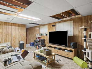 Living room featuring a paneled ceiling and wooden walls